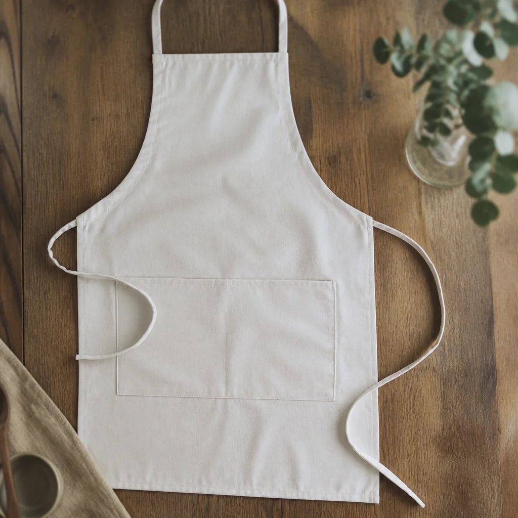 Customizable apron in white, laid flat on a wooden table