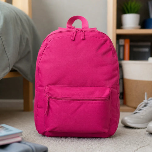 Customizable backpack in pink standing on a bedroom carpet